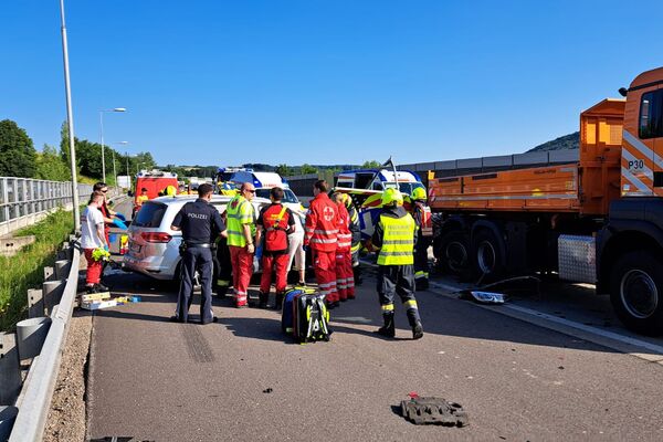 Rettungskräfte und Polizei sind an einem Verkehrsunfall auf einer Autobahn aktiv, Fahrzeuge sind beschädigt.