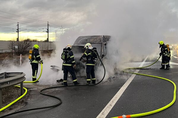 Feuerwehrleute löschen einen brennenden Einsatzwagen auf der Straße, umgeben von dichtem Rauch. | © Name
