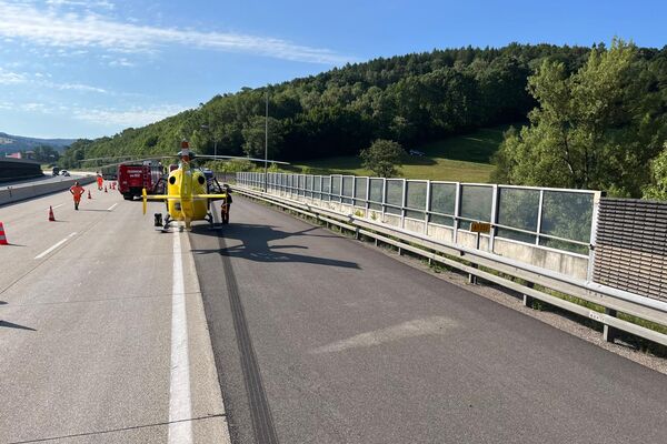 Ein gelber Hubschrauber steht auf der Autobahn, während Einsatzkräfte die Situation sichern. | © Name