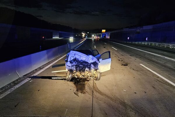 Ein schwer beschädigtes Auto steht auf der Autobahn bei Nacht, umgeben von Sicherheitslichtern und Absperrungen.