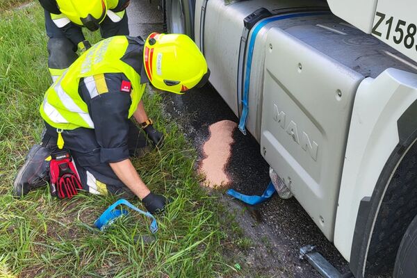 Zwei Feuerwehrmänner untersuchen den Boden neben einem Lkw und reinigen eine ausgelaufene Substanz. | © Name