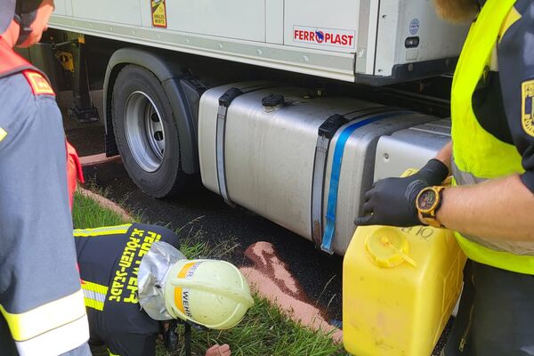 Feuerwehrleute überprüfen einen Lkw auf Lecks, während sie eine gelbe Kanister bereit halten. | © Name