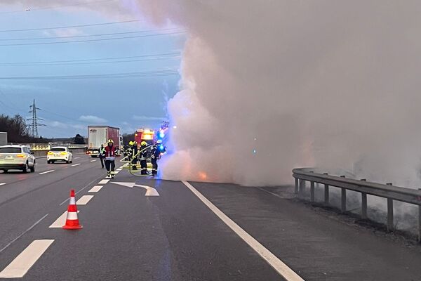 Rettungskräfte löschen einen Brand auf der Autobahn, während dichter Rauch aufsteigt. | © Name