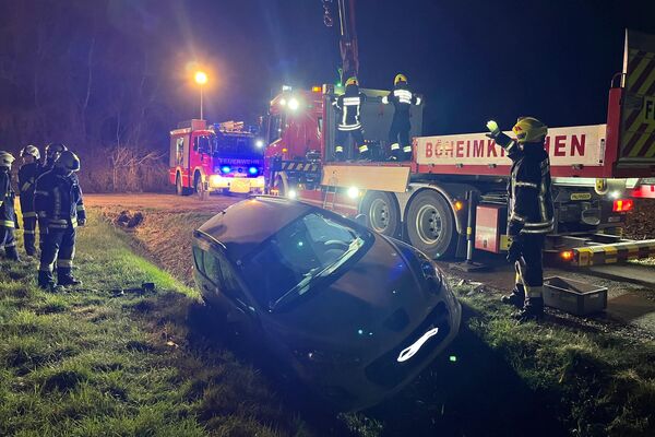 Feuerwehrleute retten ein Auto aus einem Graben bei Nacht, während ein Löschfahrzeug im Hintergrund steht. | © Feuerwehr
