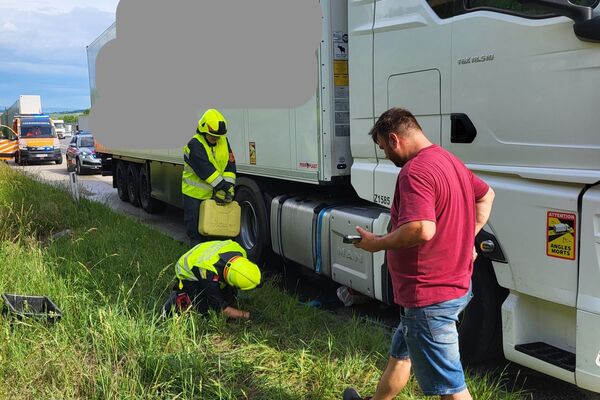 Ein Mann beobachtet zwei Helfer, die neben einem Lkw auf der Wiese arbeiten. | © Name